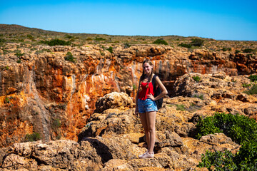 Fototapeta premium a long-haired girl sits on the edge of yardie creek gorge in cape range national park near exmouth in western australia, hiking in the wilderness of western australia