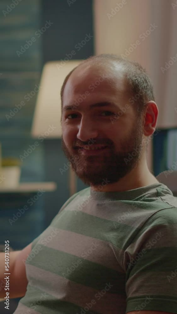 Poster vertical video: streamer man looking at camera smiling while streaming videogames using stream chat.