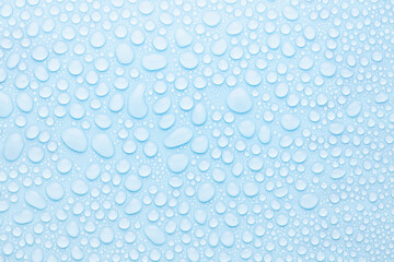Water drops on cold soft light blue background as pattern of different round glossy shine drops as dew, texture, top view.