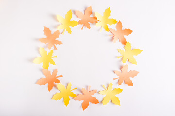A wreath of paper maple leaves on a pink background. Top view.