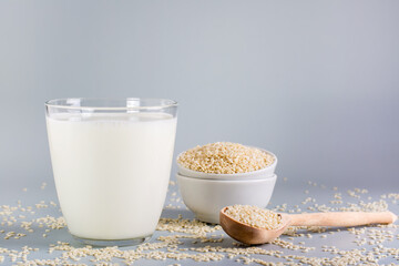Sesame milk in a glass and seeds in a bowl on the table. Dairy Alternative