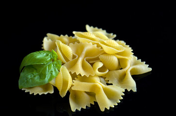 Macro Image of Uncooked Shell and Farfalle Pasta with Basil on Black Background