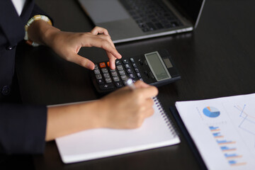 Financial planning and accounting. Accountant in an accounting firm working with financial audits and budgeting using a calculator and laptop.