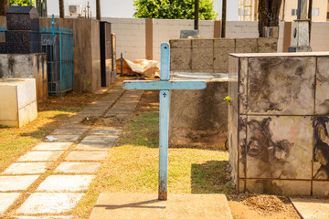 Uma cruz azul sobre um túmulo no cemitério.
