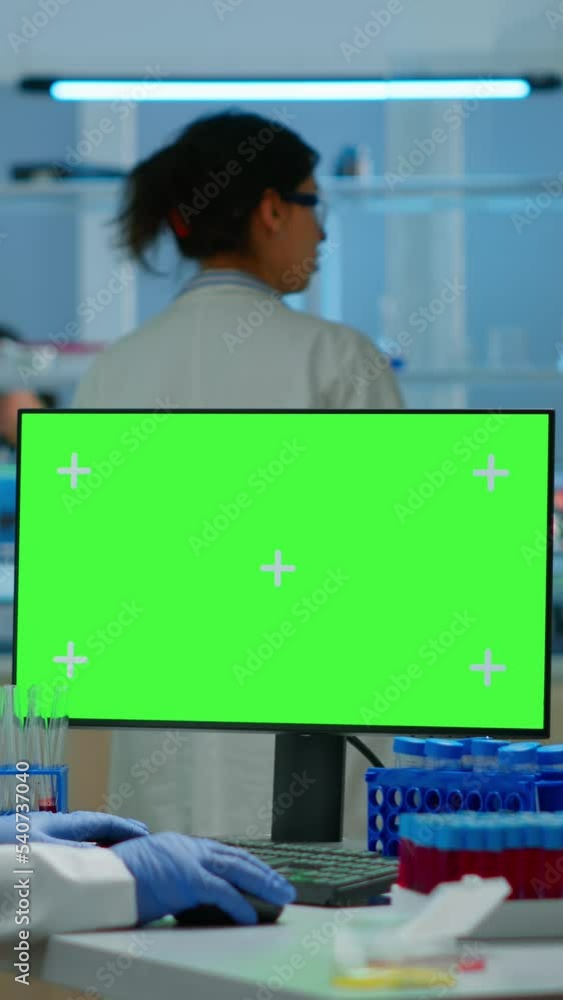 Poster vertical video: man researcher looking at chroma key display in modern equipped lab typing on comput