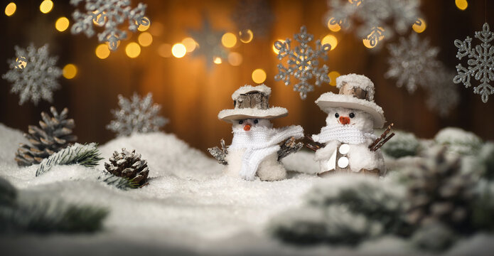 Christmas scene with snowman and hanging ornaments, wood background and snow, the illuminated brown planks and lights create a festive warm mood