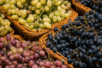 Baskets with different types of grapes on a supermarket showcase.