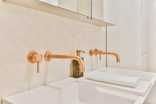 Interior of minimalist bathroom with shower and sink with copper faucets