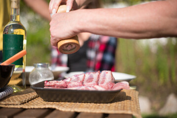 Close-up of woman preparing ribs for roasting. Female hands putting salt or spices on fresh raw meet. BBQ, cooking, food concept