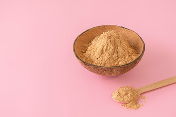 Raw organic maca root powder on soft pink background with copy space