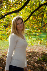 Portrait of young blonde caucasian woman standing in autumn park