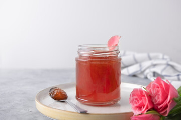Rose petal jam in a glass jar on neutral grey kitchen table with copy space - obrazy, fototapety, plakaty