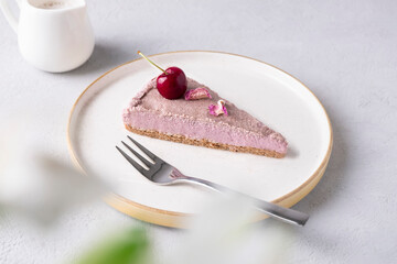 Slice of healthy raw vegan cherry cake on white plate on neutral background