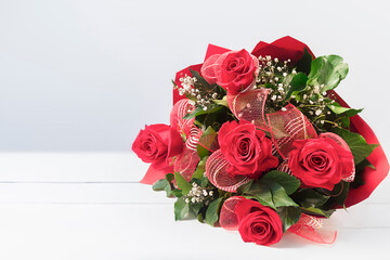 Red roses bouquet over white wooden table. Women's day background. with copy space