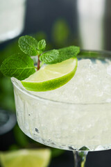 Margarita cocktail with lime, tequila, mint and ice on dark table with amazing backlight, copy space. Classic Margarita or Daiquiry Cocktail. Bar card or counter concept. Selective or soft focus.