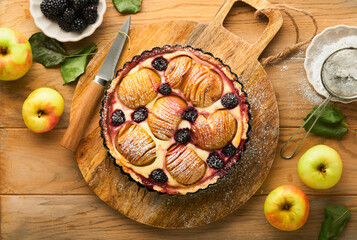 Apple pie. Apple and blackberries cake or pie decorated sugar powder on old wooden table. Delicious dessert for autumn or winter dinner. Autumn pastry dessert. Top view.