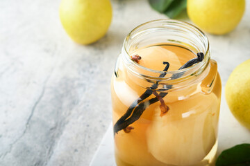 Canned pear compote with vanillin. Pear compote. Homemade delicious canned pear compote in glass jars at home on a light background. Homemade food. Space for text.