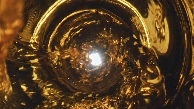 Golden liquid flowing goblet closeup. Golden lager beer waving inside glassware