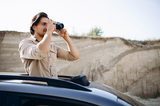 Handsome man travelling by his car and making photos on his camera