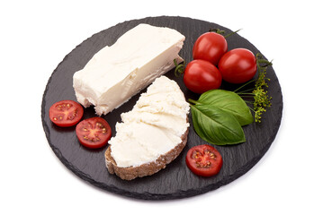 Soft feta chease on black slate stone plate with tomatoes cherry and basil leaves. Isolated on vhite background.