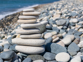 White Zen stone pyramid among beach pebbles  