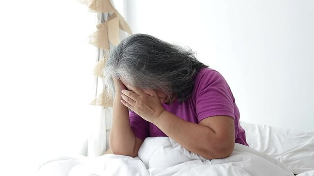 Asian elderly woman lying in bed have a headache Stressed with health problems. concept of disease problems of the elderly