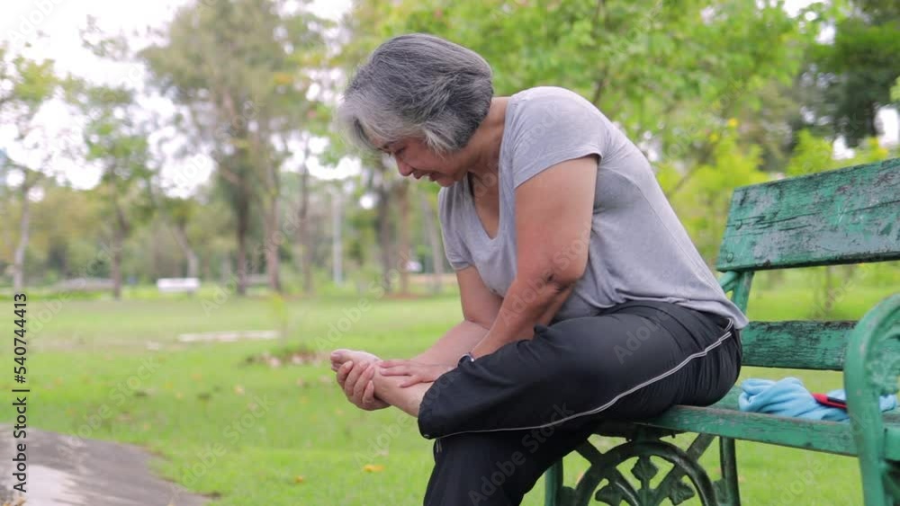 Wall mural Asian elderly woman hurts her ankle After a walk in the park. Sports concept. Senior exercise injuries