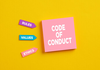 The word code of conduct on pink note paper. The components of code of conduct rules, values and...