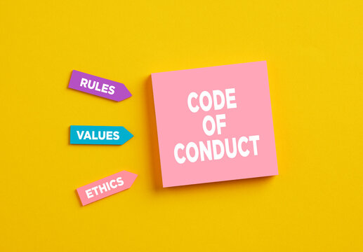 The word code of conduct on pink note paper. The components of code of conduct rules, values and ethics.