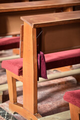 Fototapeta na wymiar Detail with wooden prayer benches in a row inside a catholic church
