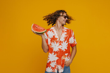 Ginger man in sunglasses laughing while dancing with watermelon