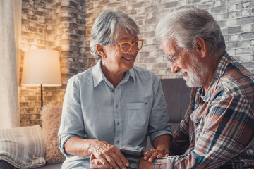 Close up and portrait of old woman checking pressure of his husband at home sitting not he sofa....