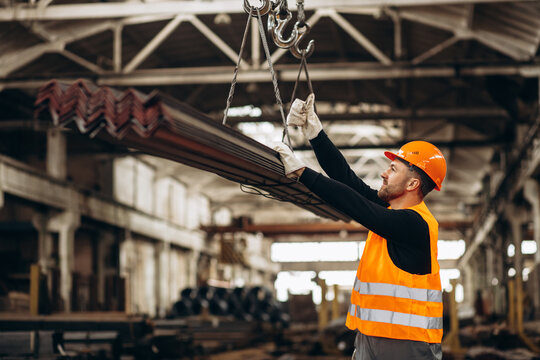 Man working at steel factory with a crane lifting steel pipes