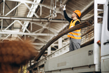 Man working at steel factory by th crane lifting steel