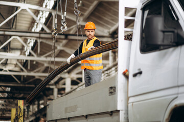 Fototapeta premium Man working at steel factory by th crane lifting steel