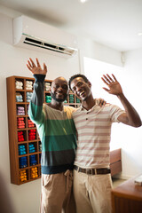 Portrait of joyful gay couple buying clothes for summer. Two happy African American men at clothing...