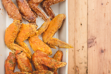 Flat lay view of a tray of assorted chicken wings on a wood table.