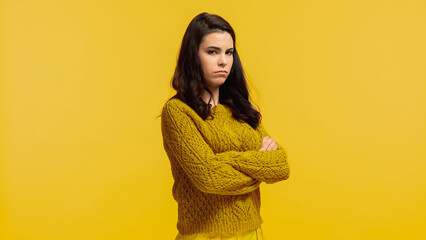 offended young woman in autumnal sweater standing with crossed arms isolated on yellow