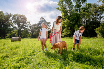 Mom with happy children and their dog walking outdoor