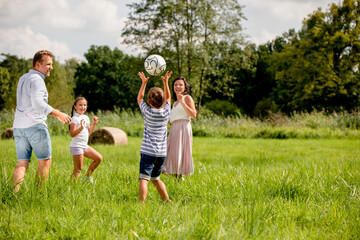 Happy family playing ball in the park on green grass