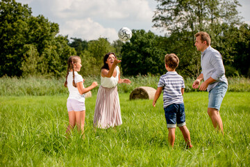 Happy family playing ball in the park on green grass