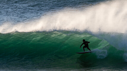 Silhouette of a surfer riding a wave at surise