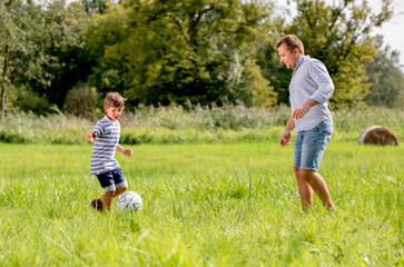 Fototapeta premium Father and daughter watching bugs in the grass using magnifying glass