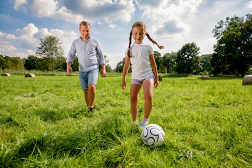 Father and daughter playing football and spending time together outdoor