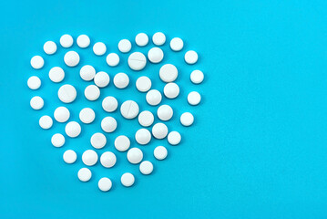 Heart-shaped white medical pills on a blue background. Tablet. Health