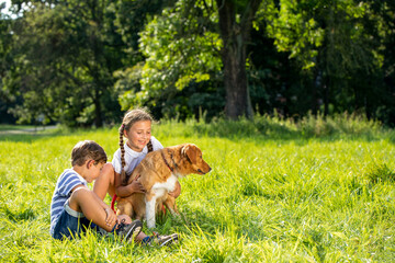 Cute siblings and their dog playing together outdoor