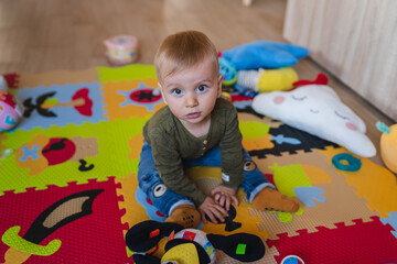 A mother and son are playing on kids carpet with toys baby is playing and sitting on the ground with toys