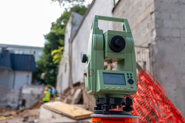 Surveying measuring equipment level theodolite on tripod at construction site with workers in background