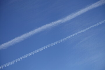 Fototapeta na wymiar Clear blue sky with two diagonal aircraft vapor exhaust background texture