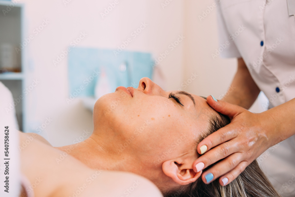 Wall mural cosmetologist does facial massage for woman. beauty skin care